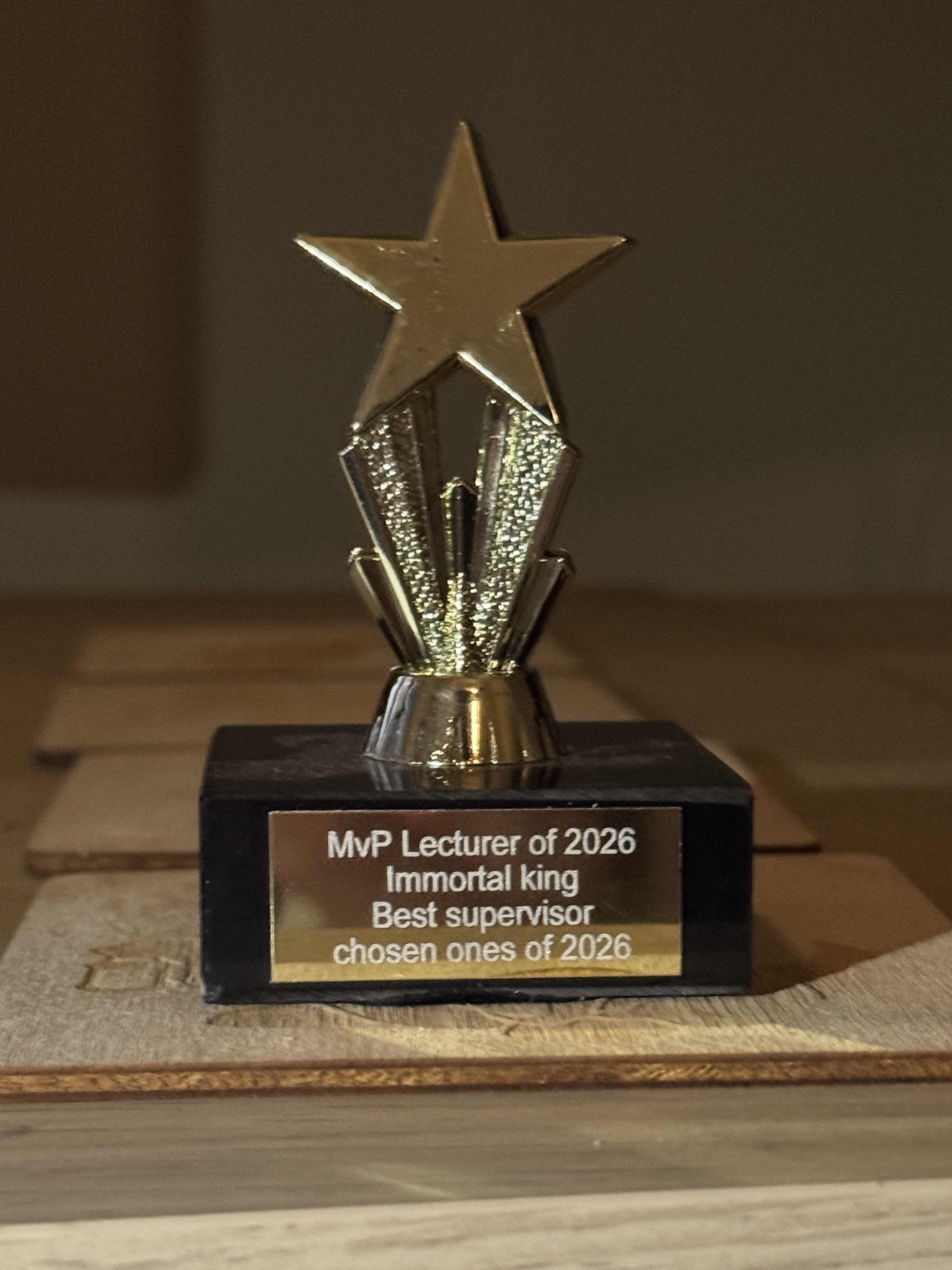 An image of a small metal award in the shape of a star. The text reads MvP Lecturer of 2026. Immortal king. Best supervisor. Chosen ones of 2026.